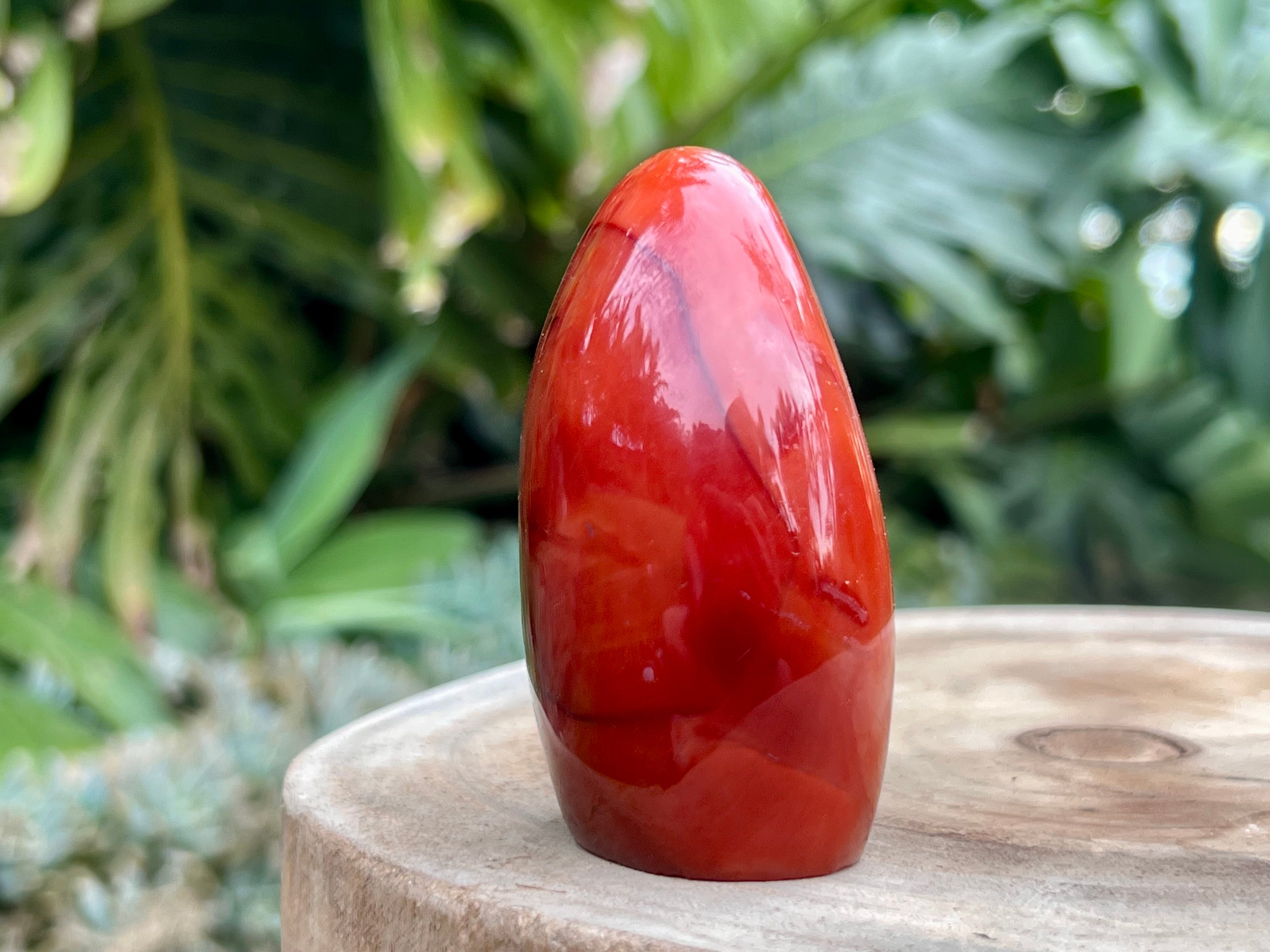 Carnelian freeform with rich orange and red swirls, polished to a glossy finish, radiating warmth, vitality, and creative energy