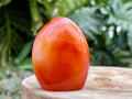 Carnelian freeform with rich orange and red swirls, polished to a glossy finish, radiating warmth, vitality, and creative energy