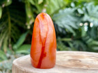 Carnelian freeform with rich orange and red swirls, polished to a glossy finish, radiating warmth, vitality, and creative energy