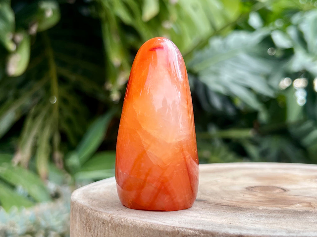 Carnelian freeform with rich orange and red swirls, polished to a glossy finish, radiating warmth, vitality, and creative energy